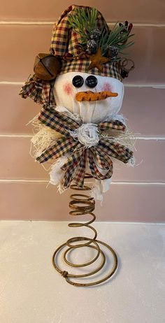 a snowman is sitting on top of a wire sculpture with sunglasses and a plaid hat