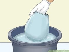 a person in white gloves is throwing something into a bucket with blue water and foam