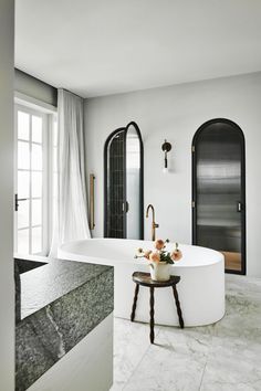 a large white bath tub sitting in the middle of a bathroom next to a window