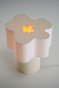 a lamp that is sitting on top of a white table with a yellow light in the middle