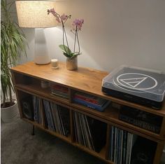 a record player sitting on top of a wooden shelf next to a vase with flowers