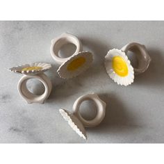 four pieces of ceramic art with yellow and white flowers in them on a gray surface