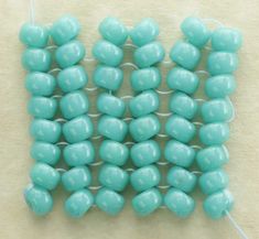 turquoise colored beads are arranged on a white surface