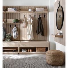 a wooden bench sitting under a mirror next to a wall mounted coat rack filled with coats