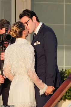 a man and woman standing next to each other in front of a camera on steps