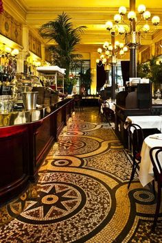 the interior of a restaurant with tables, chairs and chandeliers hanging from the ceiling