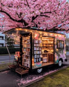 a book truck is parked under a tree with pink flowers on it's branches