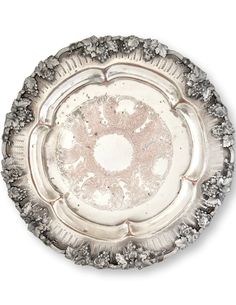 an ornate silver plate with flowers and leaves on the rim, set against a white background