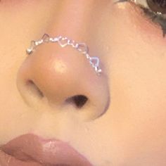 a close up of a woman's nose with a chain around her nose ring