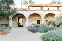 an old building with lots of plants and flowers in front of the entrance to it