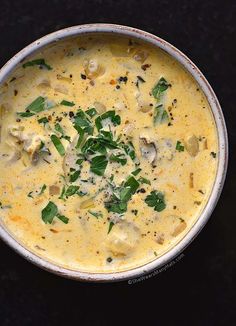 a white bowl filled with soup on top of a black table next to a spoon