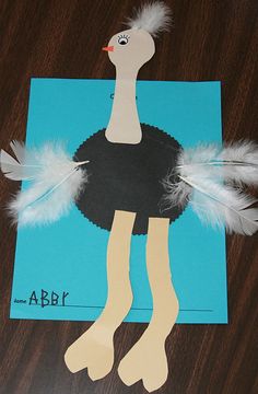 an ostrich paper cut out on top of a blue card with white feathers