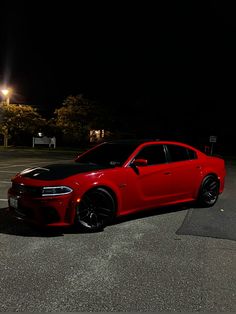 a red car parked in a parking lot at night