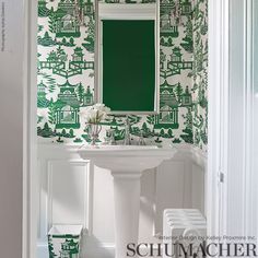 a bathroom with green wallpaper and white pedestal sink in front of the mirror on the wall