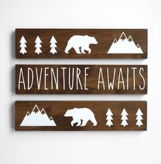 three wooden signs with the words adventure awaits and bear silhouettes in white ink