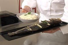 a chef is holding a plate with fish and rice