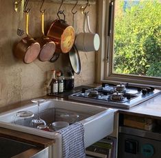 pots and pans are hanging on the wall next to an oven in a kitchen