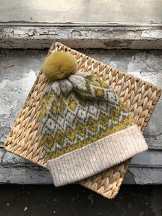 two knitted hats sitting next to each other on top of a woven piece of wood