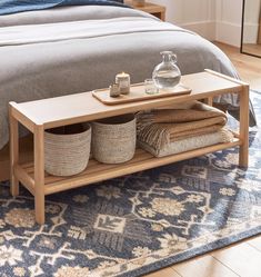 a bed sitting next to a wooden table on top of a blue rug in a bedroom