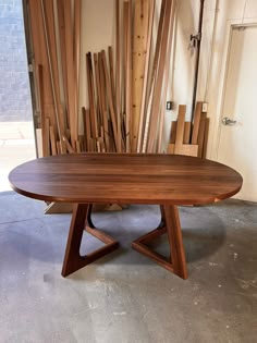 a wooden table sitting on top of a floor next to a pile of wood planks