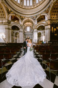 a bride and groom standing in the aisle of a church with rows of pews