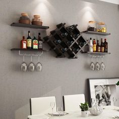 a dining room table with wine glasses and bottles on the shelves above it, next to a framed photograph