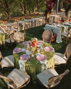 tables and chairs are set up in the grass for an outdoor dinner with flowers on them