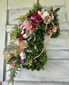 a wreath made out of flowers and greenery hangs on a door handle with an arrow