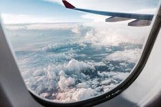 the view from an airplane window shows clouds and blue sky