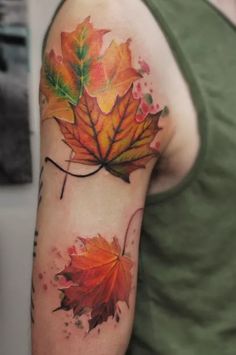 a man's arm with an orange and green leaf tattoo on it