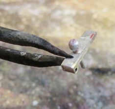 an old rusty piece of metal with nails sticking out of it's end and some rocks in the background