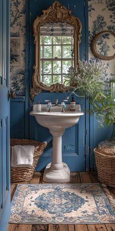 a bathroom with blue and white wallpaper, a pedestal sink and wicker baskets