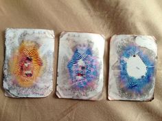 three coasters with different designs on them sitting on a tablecloth covered bed sheet