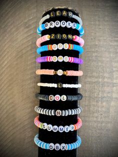 a stack of bracelets sitting on top of a black stand next to a wooden wall