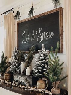 a mantel decorated with evergreens, pine cones and snowflakes in front of a sign that says let it snow