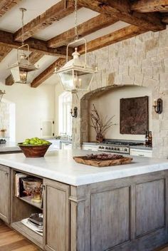 a large kitchen with an island in the center and stone walls on both sides, surrounded by wooden beams