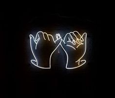 a neon sign with two hands holding each other's fingers in front of a brick wall