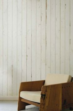 a wooden chair sitting on top of a white floor next to a wall covered in wood planks