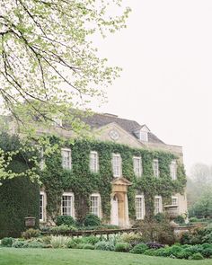 an old house with ivy growing on it's walls and trees in the foreground