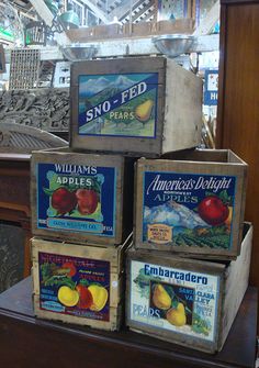 four boxes stacked on top of each other in front of a store window with apples and peaches