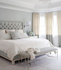 a large white bed sitting in a bedroom next to a window with drapes on it