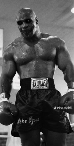 a black and white photo of a man with no shirt on, wearing boxing gloves