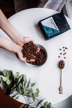 a person holding their hands over a bowl of coffee beans