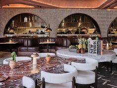 the interior of a restaurant with tables, chairs and potted plants on top of them