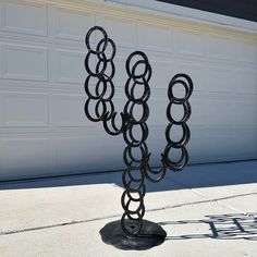 a metal sculpture with rings on it in front of a garage