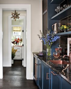 a kitchen with blue cabinets and marble counter tops is seen from the hallway to the dining room