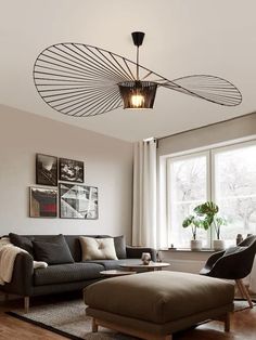 a living room with a couch, chair and ottoman under a light fixture in the ceiling