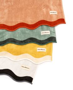 four different colors of towels on top of each other, with labels attached to them