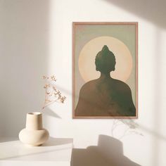 a white vase sitting on top of a table next to a wall mounted art piece