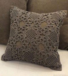 a crocheted pillow on a couch with a tag attached to the back of it